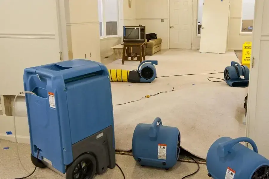 Equipment drying a Hemet living room: air movers, a dehumidifier and wet flooring partly lifted