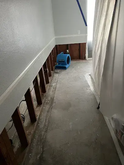 Hallway in a Perris home with flood-cut drywall and an air mover on the bare floor