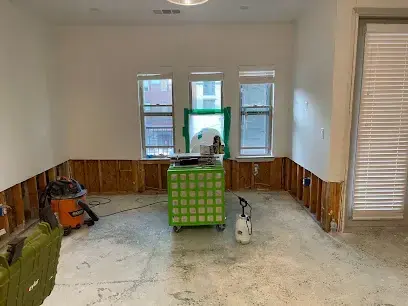 Room with the drywall cut away above the baseboard and an air scrubber running