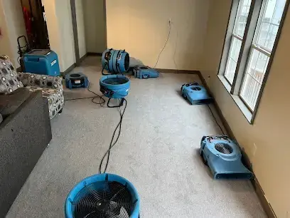 Air movers set across a carpeted living room drying a Menifee home after a water leak