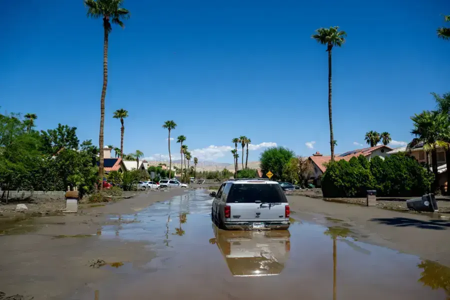 Palm-lined street under runoff after a summer tropical storm, with desert hills behind