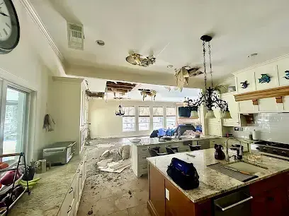 Kitchen and family room with ceiling drywall torn open after a leak from above