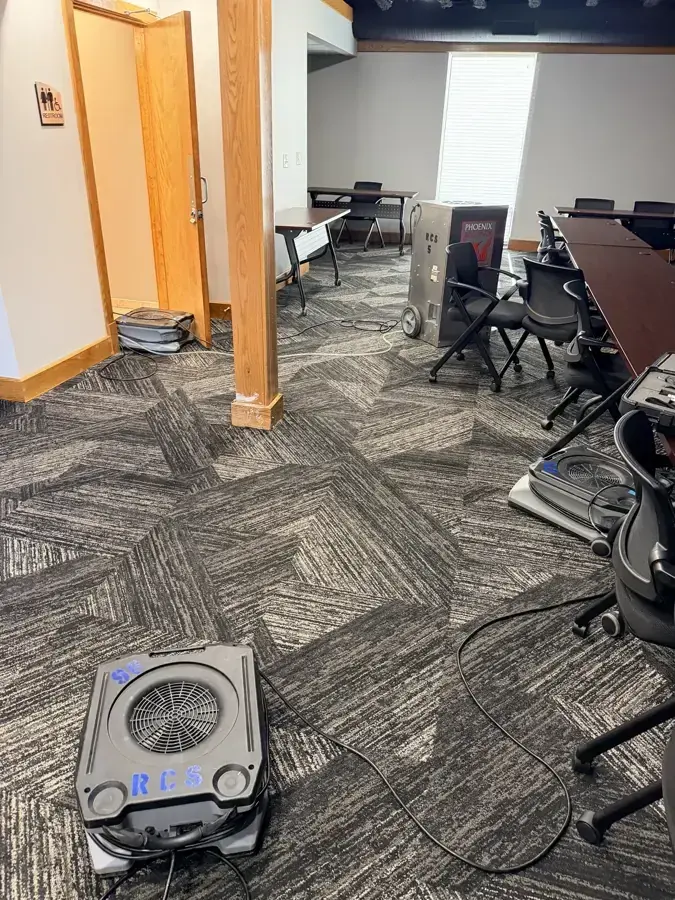 Air mover drying carpet tile in an office beside a conference room